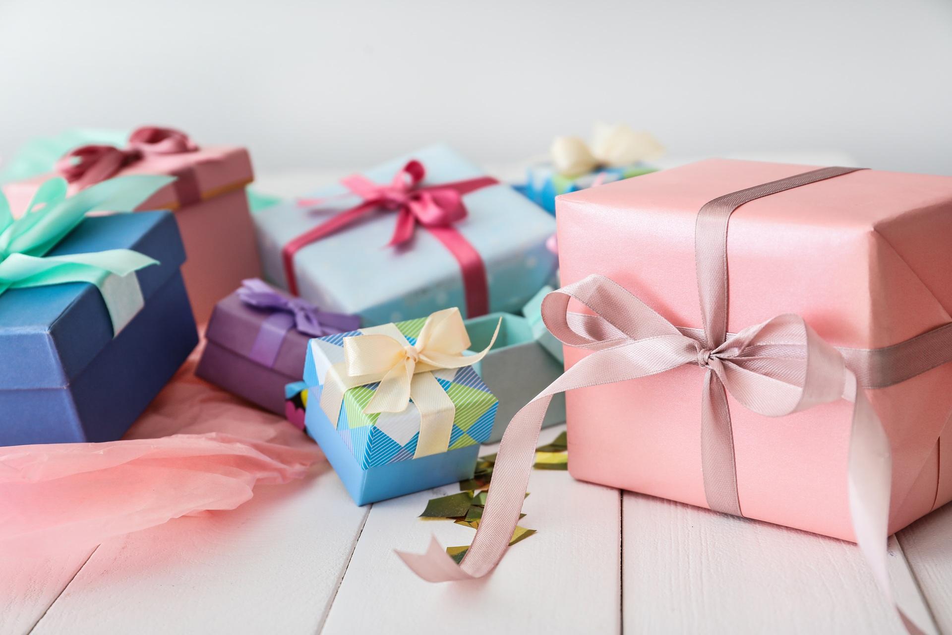 Mehrere bunte Geschenke mit Schleifen auf weißem Tisch | Präsentkorb